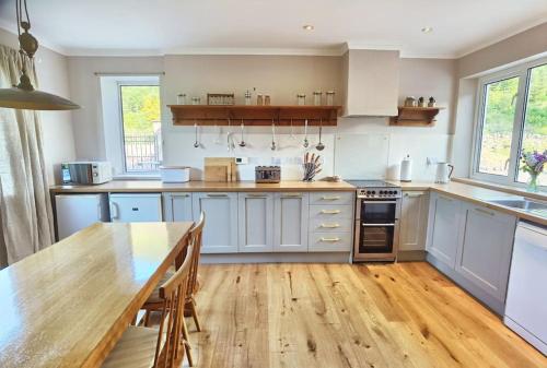 a kitchen with white cabinets and a wooden table at South Lodge, Glenfintaig in Spean Bridge