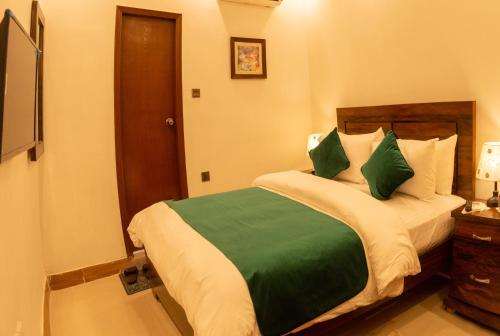 a bedroom with a bed with green and white pillows at Hotel BlueSky Clifton in Karachi