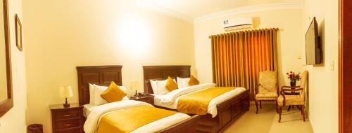 a hotel room with two beds and a chair at Hotel BlueSky Clifton in Karachi