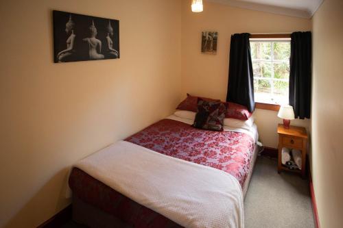a small bedroom with a bed and a window at Greenstone Retreat in Kumara