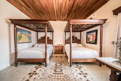 two beds in a bedroom with a wooden ceiling at Hotel La Casa de las Sirenas in Tlacotalpan