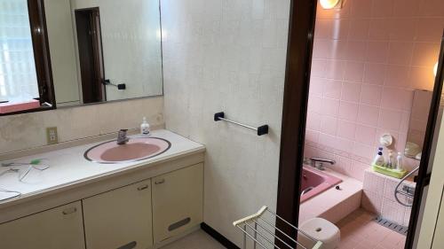 a bathroom with a sink and a pink tub at 農家民宿　たなか in Suzu