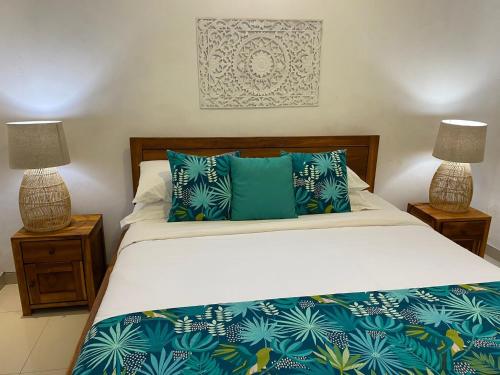 a bedroom with a bed with blue pillows and two lamps at Villa Tenang Legian in Legian
