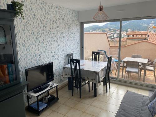 a living room with a table with chairs and a television at Studio Climatisé à Banyuls-sur-Mer, Terrasse, WIFI, Proche Plage - FR-1-309-323 in Banyuls-sur-Mer