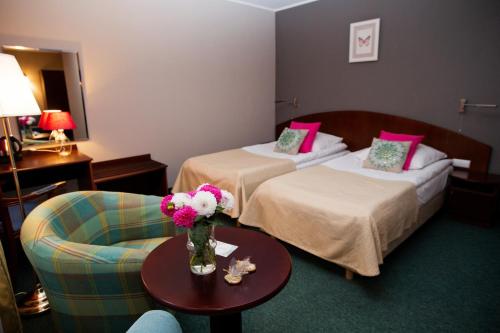 una habitación de hotel con 2 camas y una mesa con flores en Hotel Rezydencja Solei, en Poznan