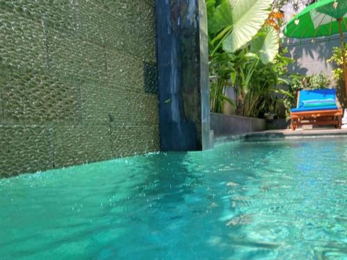 a swimming pool with a chair and an umbrella at Villa Tenang Legian in Legian