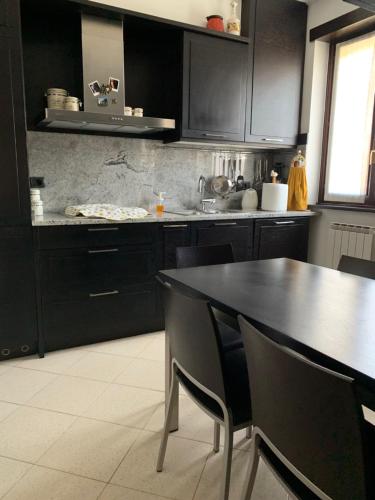 a kitchen with black cabinets and a black table and chairs at Near Como, charming apartment with fireplace in Grandate