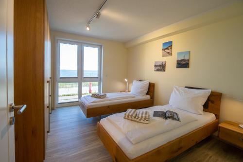 a hotel room with two beds and a window at Weiße Düne Ferienwohnung *Weiße Düne 6* in Wittdün