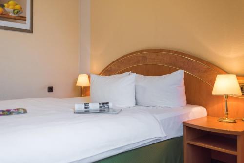 a hotel room with a bed with white sheets and pillows at Lohmann's Kapeller Hof in Langenfeld