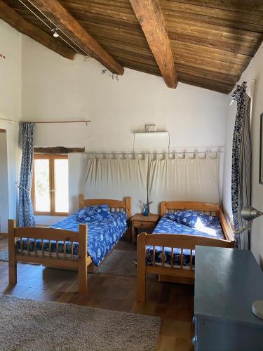 deux lits dans une chambre avec plafonds en bois dans l'établissement La Colle en Provence Main House, à Sigonce