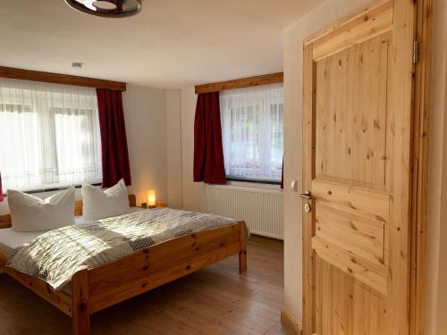 um quarto com uma cama e uma porta de madeira em Naturhof Kluge em Saupsdorf