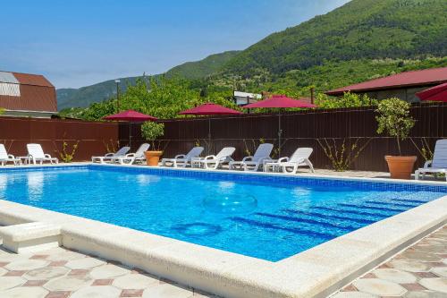 a swimming pool with lounge chairs and a mountain at Отель Taminik in Gagra