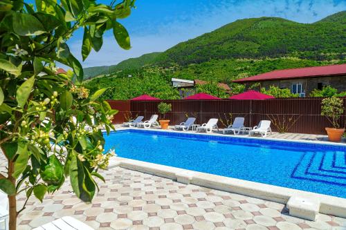 a swimming pool with chairs and a mountain in the background at Отель Taminik in Gagra