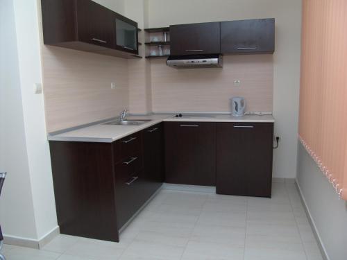 a kitchen with dark brown cabinets and a sink at Апартаменти СЪНИ БЕЙ in Sunny Beach