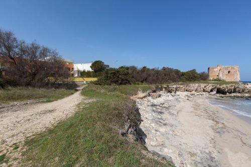 a dirt road next to a beach with a castle at Residence Solaris in San Foca