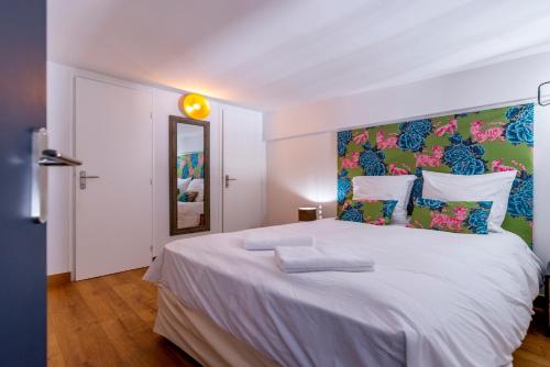 - une chambre avec un grand lit blanc et une tête de lit colorée dans l'établissement 