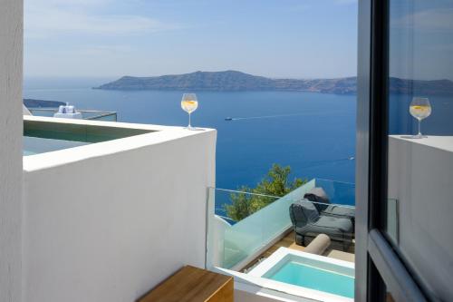 a view of the ocean from a house with glasses of wine at Agnadema Apartments in Firostefani