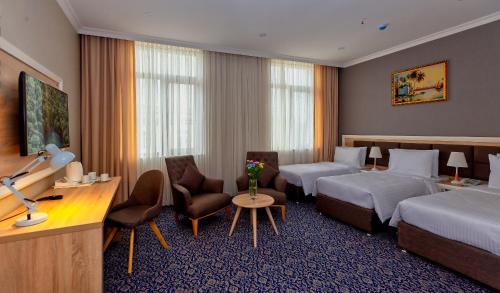 Golden City Hotel Baku في باكو: غرفة فندقية بسريرين ومكتب وكراسي