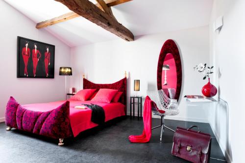 a bedroom with a red bed and a mirror at La Villa des Forges in Legé