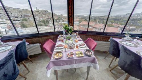 uma sala de jantar com mesas, cadeiras e janelas em Cappadocia Alaz Cave Otel em Nevşehir