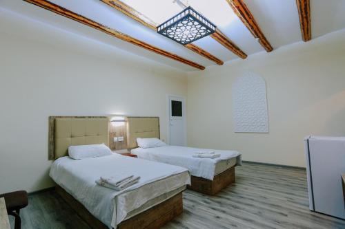 two beds in a room with white walls and a skylight at BUKHARA HOUSE hotel in Bukhara