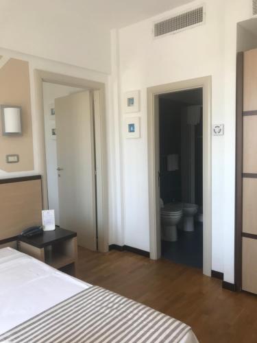 a bedroom with a bed and a bathroom with a toilet at Hotel Royal in San Benedetto del Tronto