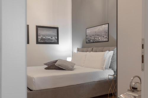um quarto com uma cama branca e duas fotografias na parede em San Niccolò Luxury Apartment em Florença