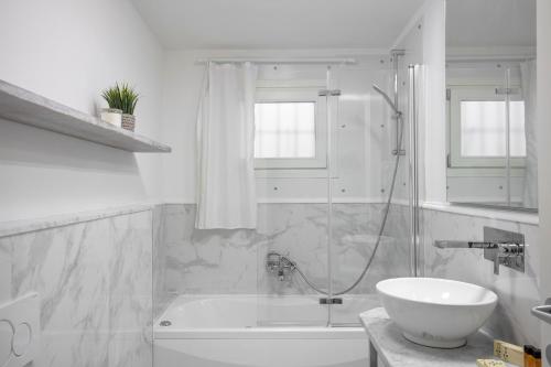 uma casa de banho branca com uma banheira e um lavatório em San Niccolò Luxury Apartment em Florença