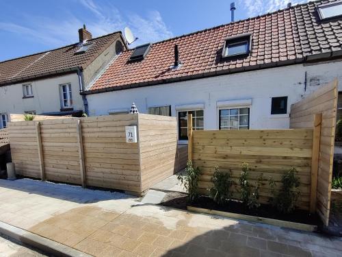 una recinzione di legno di fronte a una casa di Le petit blanc a De Haan