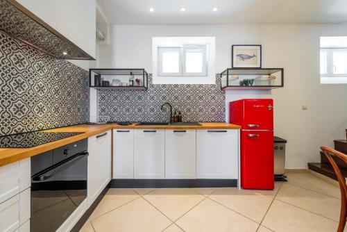 a kitchen with white cabinets and a red refrigerator at Villa Lizza in Cavtat