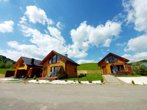 two wooden houses are sitting on the side of a road at Domki pod Bukowym lasem in Wańkowa