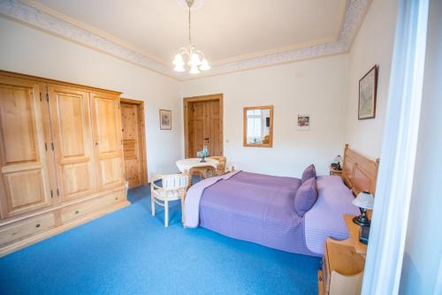 a bedroom with a purple bed and a table at Bilz-Pension in Radebeul