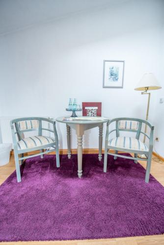 two chairs and a table with a purple rug at Bilz-Pension in Radebeul