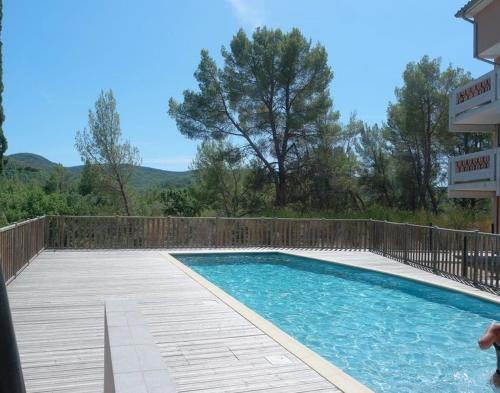 - une piscine avec une terrasse en bois à côté d'un bâtiment dans l'établissement Terrasse 130m2 panoramique avec Climatisation Piscine - 3 chambres, à Gréoux-les-Bains