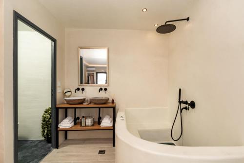 a bathroom with a white tub and a mirror at Saint Sin Suites - Adults Only in Imerovigli