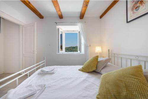 a white bedroom with a bed and a window at Villa Lizza in Cavtat