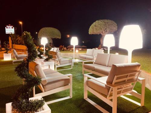 a group of white lounge chairs on the grass at night at Apartamentos Esperanza del Mar in Portonovo