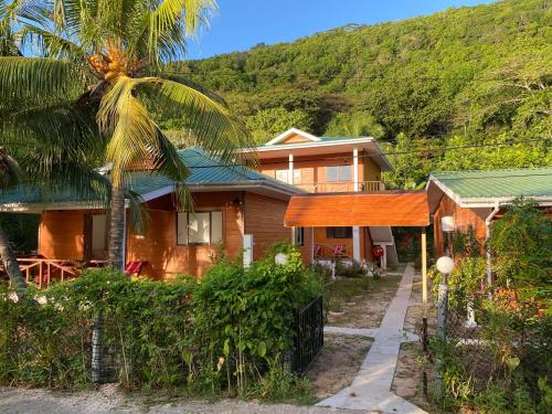 a house with a palm tree in front of it at Anse Grosse Roche Beach Villa in La Digue