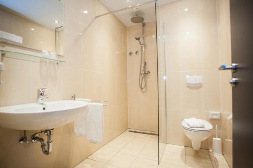 a bathroom with a shower and a sink and a toilet at Hotel Winterberg Resort in Winterberg