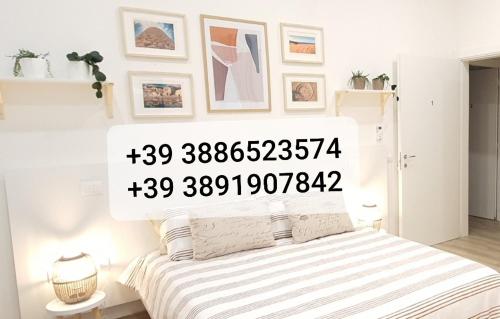 a white bedroom with a bed with a striped blanket at SUITE BLANC APARTMENTS - Monolocali indipendenti con cucina e bagno privato - Check-in e check-out con codice in autonomia h24 - Terrazza in comune NECESSARIO AVERE WATHSAPP O APP DI MESSAGGISTICA ISTANTANEA PER FOTO E VIDEO in Guspini