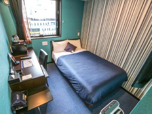 a small room with a bed and a desk at HOTEL LiVEMAX Numazu Ekimae Hotel in Numazu