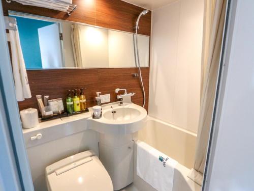 a bathroom with a sink and a toilet and a mirror at HOTEL LiVEMAX Numazu Ekimae Hotel in Numazu