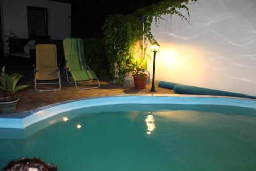 a large blue swimming pool with a lamp and chairs at Penzion v Budech in Křivoklát