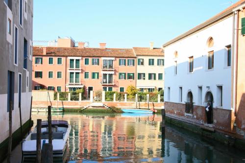 a boat in a canal in a city with buildings at Hotel Giudecca Venezia in Venice