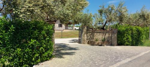 a gate in a hedge with a house in the background at Villa Klinai in Cerveteri