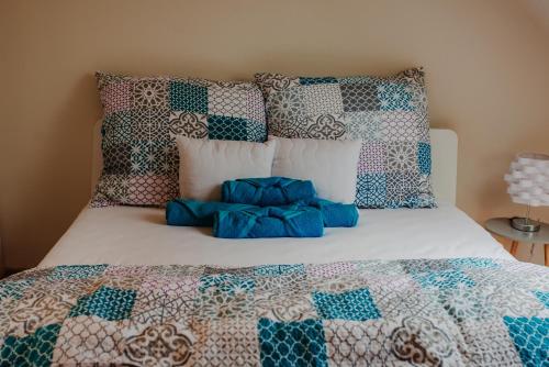 ein Bett mit einer blauen und weißen Decke und Kissen in der Unterkunft Kamilla Apartman in Makó
