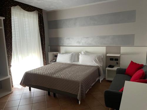 een slaapkamer met een bed en een bank bij Hotel Villa Rosa in Sirmione