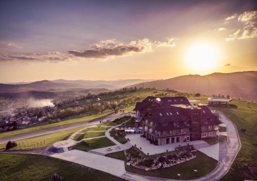 an aerial view of a building with the sun in the background at Złoty Groń Resort & Spa in Istebna