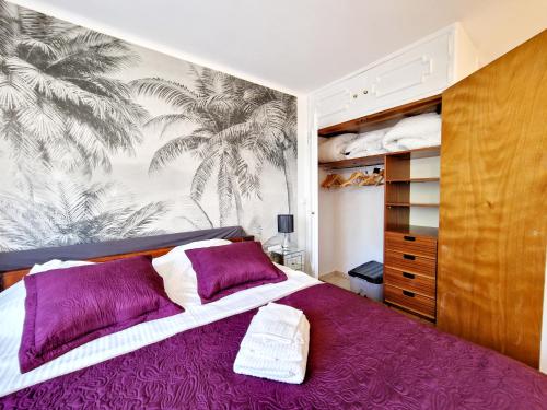 1 dormitorio con cama morada y mural de palmeras en Cannes Appartement Palais Festivals, en Cannes