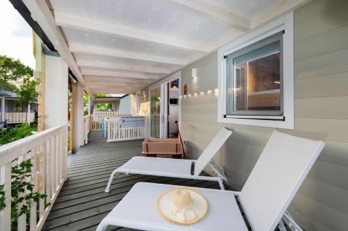 a porch with white chairs and a hat on it at Camping Union Lido in Cavallino-Treporti
